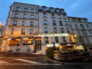 een groot gebouw met een restaurant ervoor bij Paris Saint Cloud Hôtel in Saint-Cloud