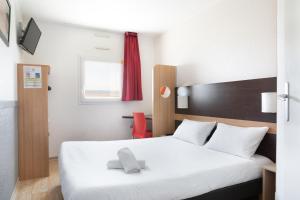 a bedroom with a white bed and a red chair at Premiere Classe Nice - Promenade des Anglais in Nice