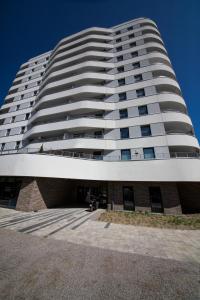 a tall white building with a blue sky in the background at Wyspa Uznam Sun Tower in Świnoujście