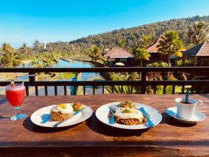 einen Tisch mit 2 Tellern Essen und einem Getränk in der Unterkunft Villa Sande in Munduk