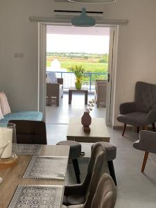 een woonkamer met een tafel en stoelen en een balkon bij Casa Azzuro - Luxurious Modern Apartment Kapparis in Paralimni