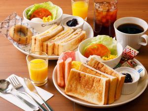 a plate of food with sandwiches and salad and juice at JR Inn Sapporo Kita 2 Jo in Sapporo