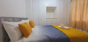 a bedroom with a bed with yellow and white pillows at Marahomes in Bushey