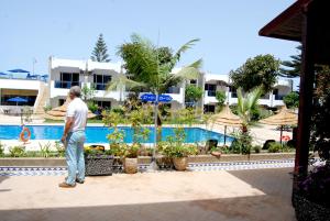 un homme debout en face d'une piscine dans l'établissement Hotel Al Khaima, à Assilah