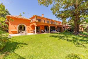 una casa naranja con césped delante en Villa Hacienda del Mar, en Marbella