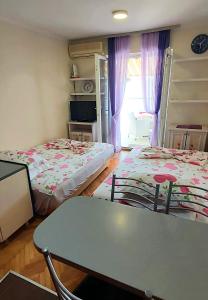 um quarto com duas camas e uma mesa e uma janela em Sunčani apartman 1-Vila Amfora em Budva