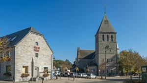 a church with a tall tower with a clock on it at Hotel Au lit des ours in Han-sur-Lesse