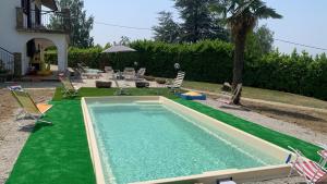 a swimming pool with a green floor and chairs at La casa di Valentina in Bossolasco