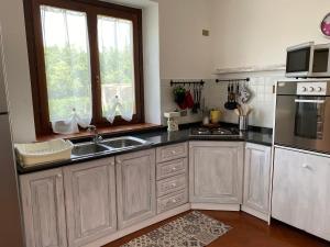 a kitchen with white cabinets and a sink and a refrigerator at La casa di Valentina in Bossolasco