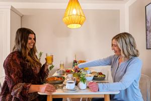 zwei Frauen sitzen an einem Tisch und essen Essen in der Unterkunft Ferien-Apartment Riedperle mit Privatstrandzugang in Friedrichshafen