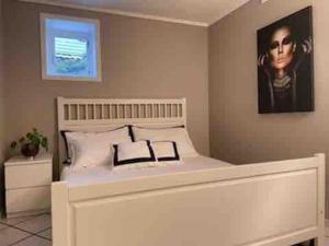 a bedroom with a white bed with a picture on the wall at Sentrumsnær leilighet med 3 soverom. in Bergen