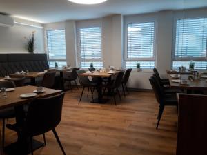 un ristorante con tavoli e sedie in legno e finestre di Hotel Weinert a Neubrandenburg
