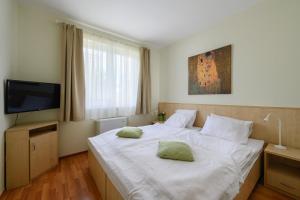 1 dormitorio con 1 cama blanca y 2 almohadas en Mirage Wellness Apartman, en Hajdúszoboszló