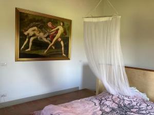 una cama con cortina y una pintura en la pared en Casale Mavianda, en San Lorenzo Nuovo