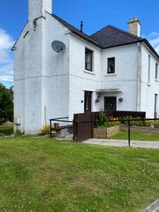 a large white house with a fence in front of it at No 5 Newly refurbished 4 bedroom house in Cononbridge