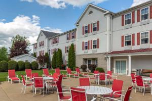 a patio with red chairs and tables in front of a building at Comfort Inn & Suites in Hadley