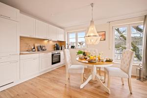 a kitchen with a dining room table with white cabinets at Ferien-Apartment Irisblüte - mit priv Strandzugang in Friedrichshafen