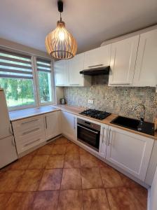 a kitchen with white cabinets and a stove top oven at Apartament 5 minut spacerem od plaży in Giżycko
