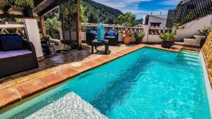 a swimming pool in the middle of a patio with chairs at Casa La Higuera Competa by Ruralidays in Frigiliana