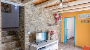 a living room with a tv and a stone wall at Casa La Higuera Competa by Ruralidays in Frigiliana