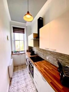 a kitchen with white cabinets and a sink and a window at Anchored Homely Apartment in Historic Centre in Paisley