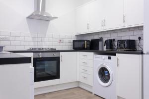 a white kitchen with a washing machine and a washer at Boaler House, modern 4 Bed House with parking Sleeps 8 in Liverpool