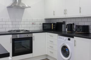 a white kitchen with a washer and a stove at Boaler House, modern 4 Bed House with parking Sleeps 8 in Liverpool