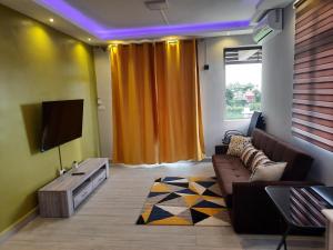 a living room with a couch and a tv at Nivi Cosy Appartment in Flic-en-Flac