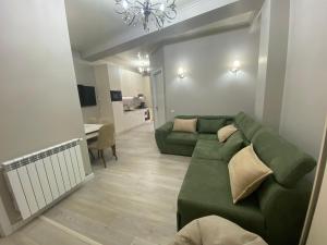 salon z zieloną kanapą i stołem w obiekcie Home № 1 w Kutaisi