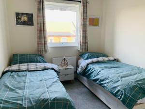 Alpha, Private Double Room, City Centre, Free Parking, Sittingbourne, Kent في سيتينغبورن: سريرين توأم في غرفة نوم مع نافذة +صورتان