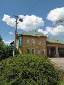 a yellow building with a green roof on a street at Kaufman in Konopnitsa