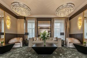 sala de estar con sofá, sillas y lámparas de araña en St Palace Hotel, en Vilna