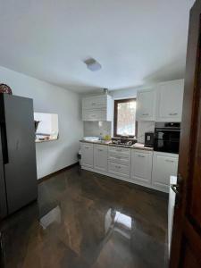 an empty kitchen with white cabinets and a window at Silver Mountain Villa Colibita in Colibiţa
