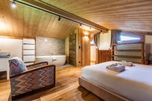 1 dormitorio con 1 cama y bañera en una habitación en Apartment Tahoe Les Gets - by EMERALD STAY, en Les Gets