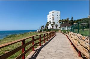 a wooden boardwalk next to the beach with a building at BEACH ALMIRANTE 9 MIJAS Marbella in Sitio de Calahonda