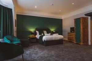 a bedroom with a bed and a green wall at The Stag Hotel and Mailmans Arms in Lyndhurst