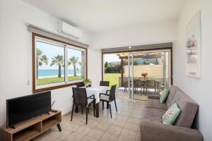 a living room with a couch and a tv and a table at Pebble Beach Apartment in Oroklini