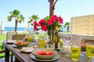 a table with food and flowers and wine glasses at Pebble Beach Apartment in Voroklini