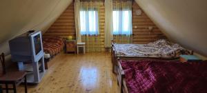 a attic room with two beds and a television at Saulėtekio 12 in Ignalina