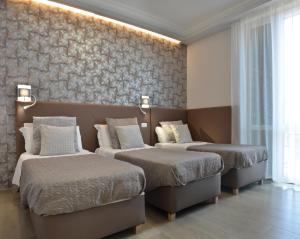 a bedroom with two beds and a wall with wallpaper at At your Place in Rome