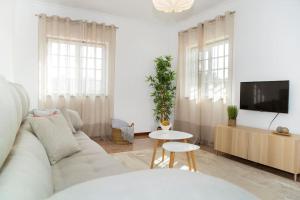 a white living room with a white couch and a tv at EntreVillas Alojamento Local, apartamento T2 in Arcos de Valdevez