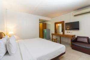 パタヤ・ノースにあるサワディー プレイスのベッド、ソファ、テレビが備わるホテルルームです。