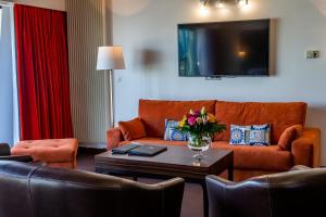 a living room with a couch and a tv at Hotel Le Grand Pavois in Fécamp