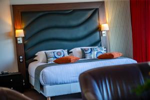 a bedroom with a bed with a blue headboard and pillows at Hotel Le Grand Pavois in Fécamp