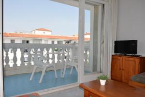 a living room with a balcony with a tv and chairs at APCOSTAS Europa in Blanes