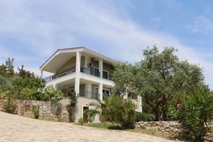 a white house with a stone wall and trees at FANTASY GRAND VILLA THASSOS in Astris