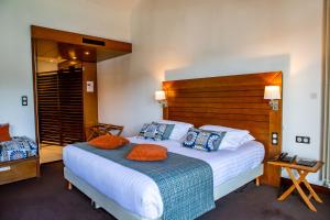 a hotel room with a large bed with orange pillows at Hotel Le Grand Pavois in Fécamp