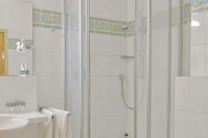 ein weißes Bad mit einer Dusche und einem Waschbecken in der Unterkunft Seehof Seehof 31 in Bansin