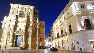 a large building with a clock tower in a street at SANTA CHIARA SUITE HOTEL & SPA - Lecce in Lecce