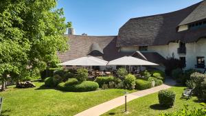 a courtyard with tables and umbrellas in front of a building at La Flambée in Sennecey-lès-Dijon